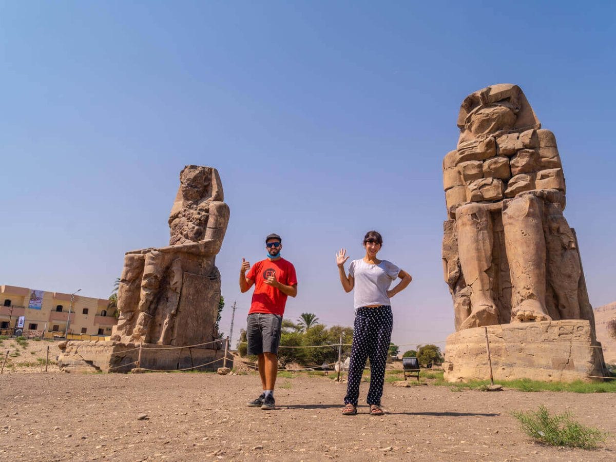 Tourists exploring colossal statues at the ancient Memnon Colossi in Egypt. Book your Egypt tours now!