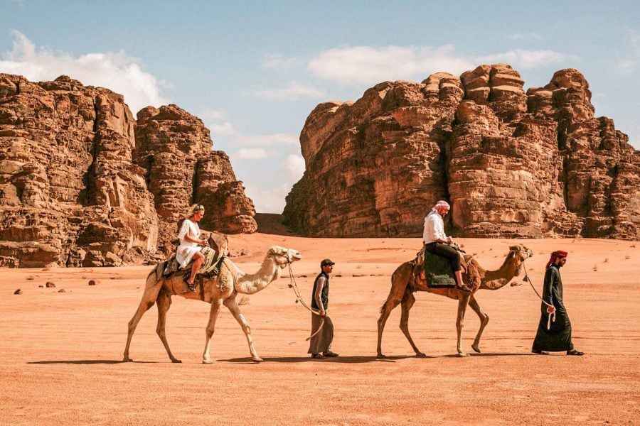 Tourists camel trekking Wadi Rum, Jordan's stunning desert landscape. Experience unique desert adventures.