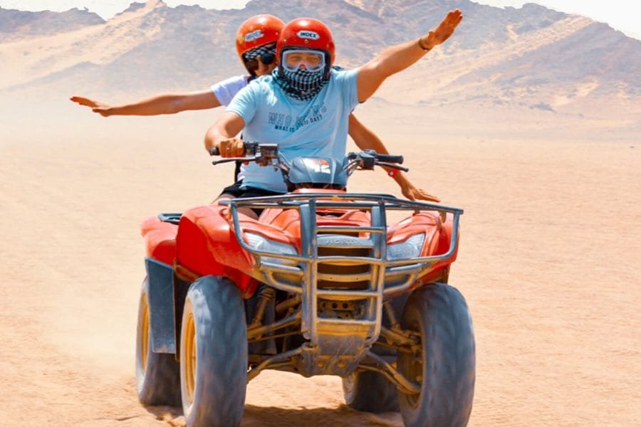 Couple enjoying exhilarating ATV ride through Egypt's desert landscape. Egypt tours adventure.