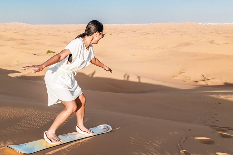 Great picture of a woman sandboarding in the desert
