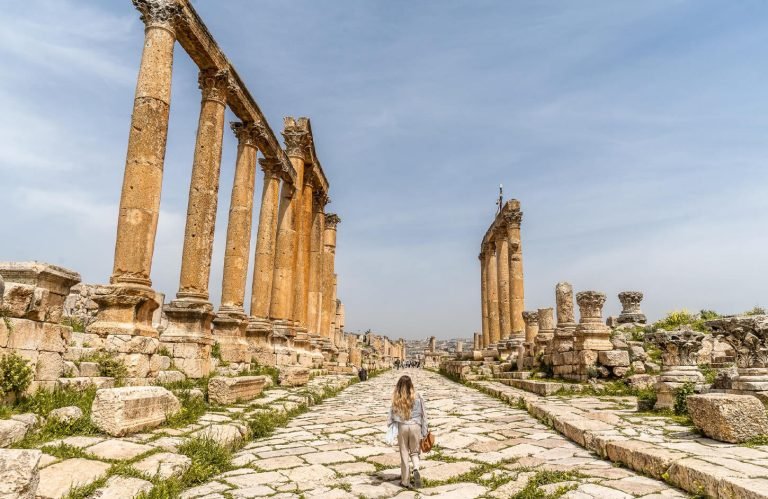 Traveler walking down the main street lined with massive columns at the Temple of Artemis in Jerash, Jordan