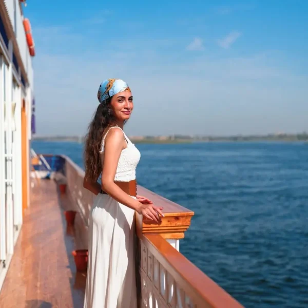 A woman in a white dress enjoys the river view on a luxury boat, illustrating how to choose the best nile cruise for comfort and style.