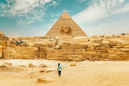 A man walks near the Great Sphinx, showcasing its iconic presence in the landscape of ancient Egypt.