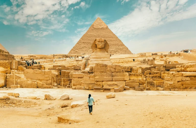 A man walks near the Great Sphinx, showcasing its iconic presence in the landscape of ancient Egypt.