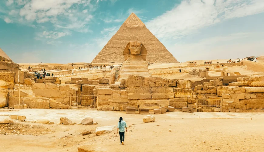 A man walks near the Great Sphinx, showcasing its iconic presence in the landscape of ancient Egypt.