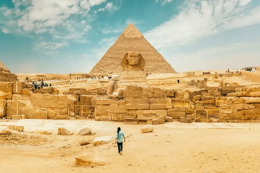 A man walks near the Great Sphinx, showcasing its iconic presence in the landscape of ancient Egypt.