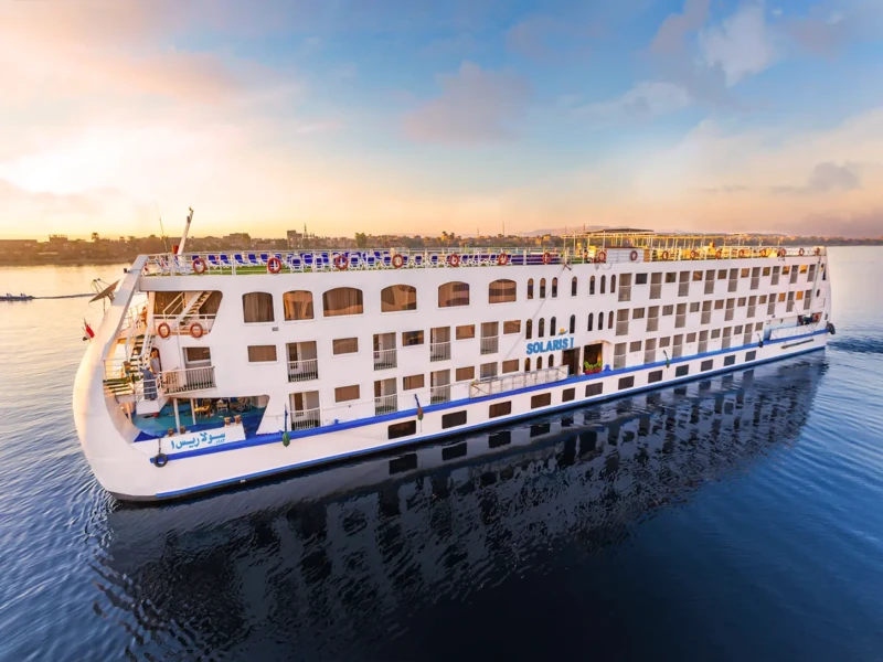 A large white boat floats on the Nile, inviting travelers to explore history on a scenic cruise.