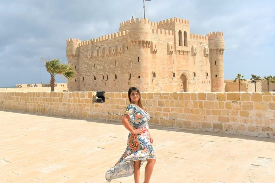 Female tourist posing in front of the historic Qaitbay Citadel in Alexandria, Egypt.