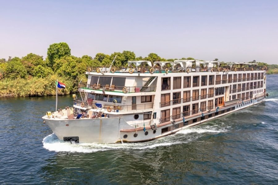 Full exterior view of the MS Nile Dolphin cruising past green riverbanks on the Nile River.