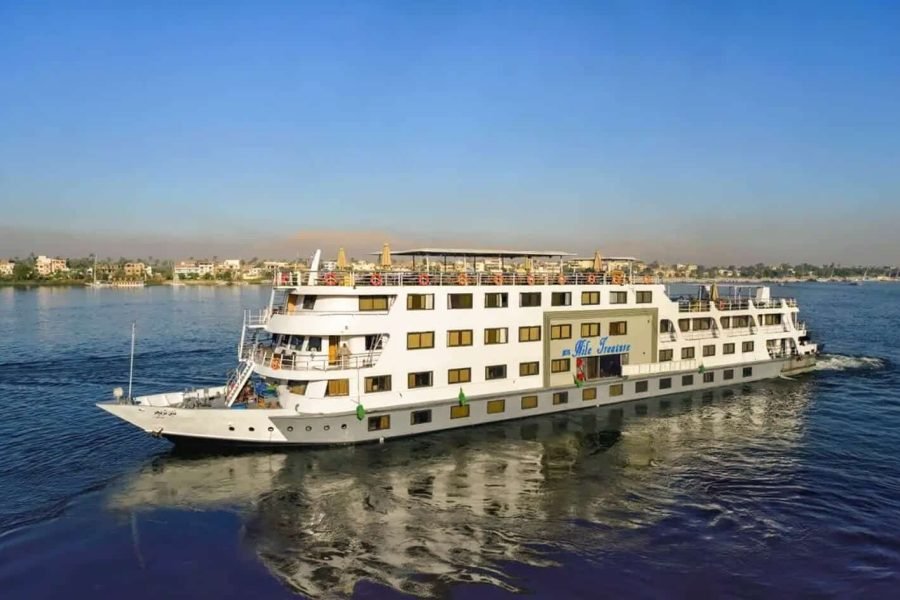 The multi-deck Nile Treasure cruise ship sailing on the Nile River on a sunny day.