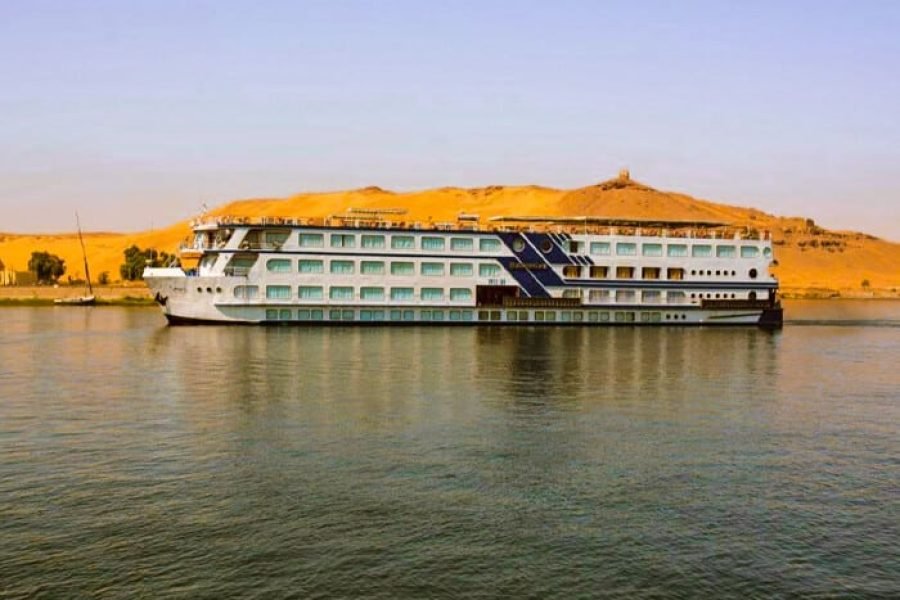 The Rhadamis II cruise ship sailing on the Nile River past large sand dunes, showcasing the Egypt river cruise.