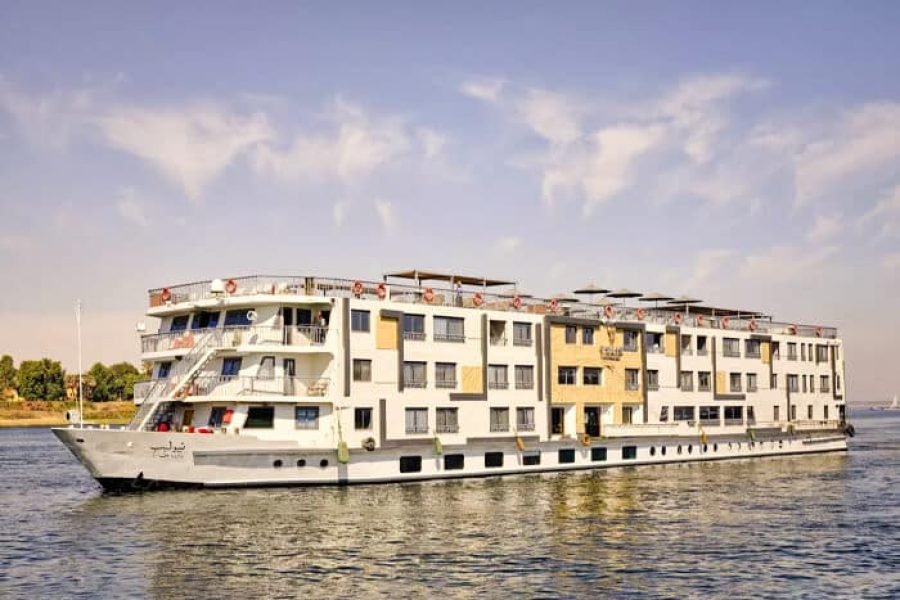 The multi-deck Tulip Nile Cruise Ship with its white and beige hull sailing on the Nile River in Egypt.
