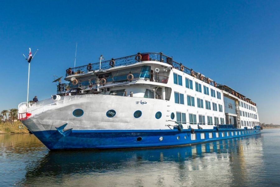 The Tuya Cruise ship sailing on the Nile River under a clear sky, promoting Egypt river cruise packages.