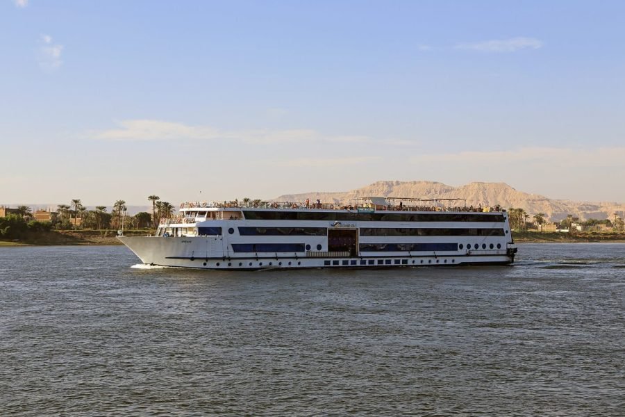 The Blue Shadow cruise ship sailing on the Nile River past mountainous terrain for an Egypt river cruise.