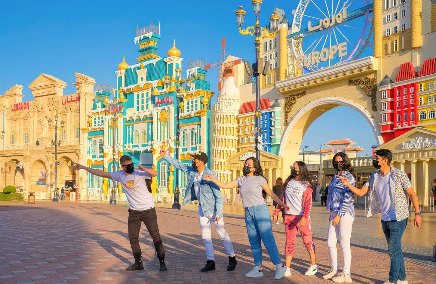 Tourists posing in front of the colorful Global Village Dubai pavilions
