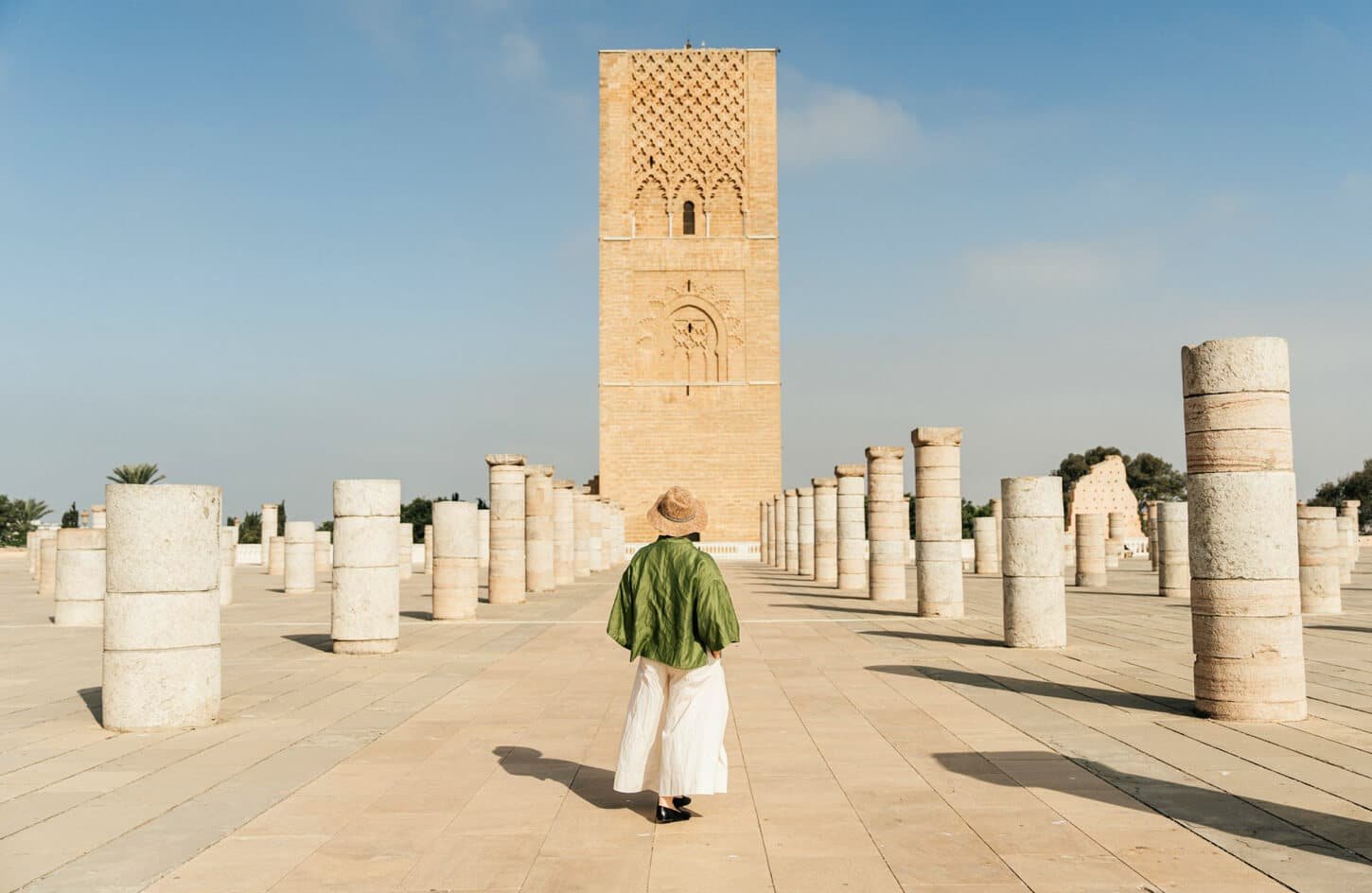 Traveler in a hat viewing the Hassan Tower and its ancient columns in Rabat, Morocco.