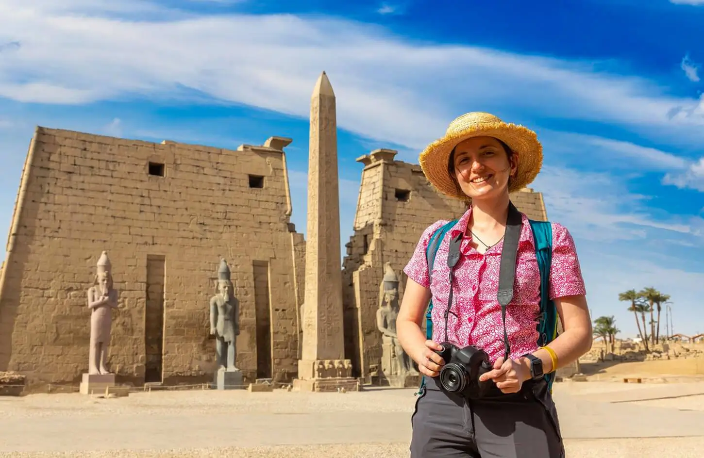 A stunning photo of a girl standing in front of Luxor Temple holding a camera