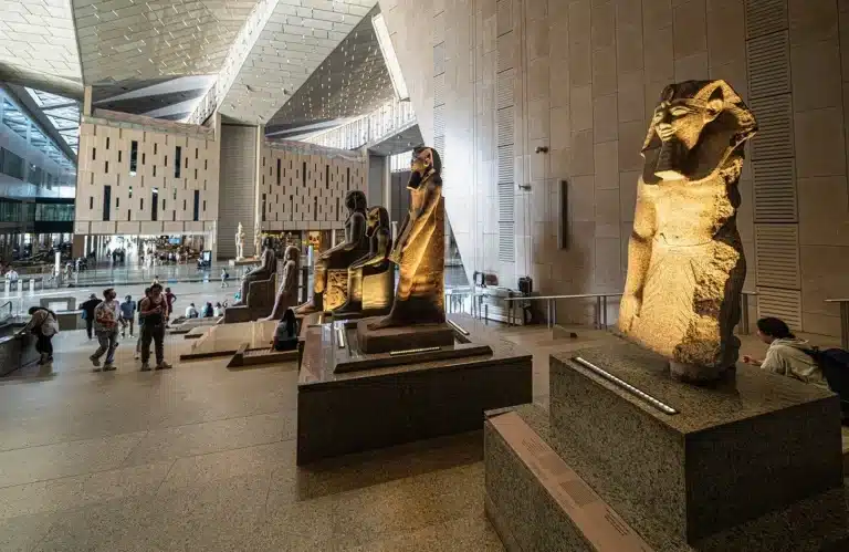 Grand Egyptian Museum interior featuring Ancient Egyptian pharaoh statues on the grand staircase in Giza.