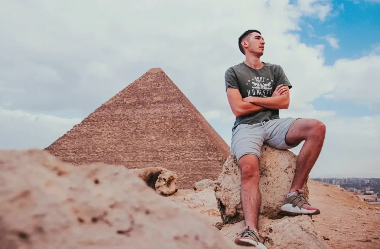 A traveler sitting in front of the Great Pyramid of Giza, showcasing iconic Egypt tourism and historical landmarks