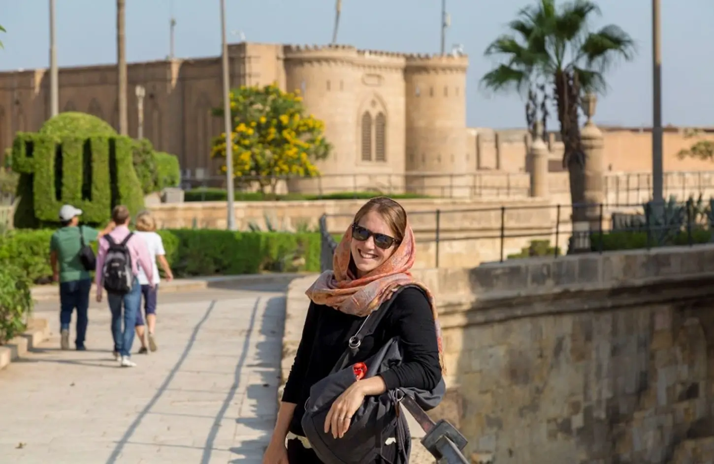 Female tourist at Saladin's Citadel in Cairo, Egypt, with historic stone fortifications in the background.