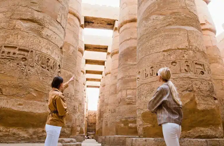 Expert tour guide in Egypt pointing out hieroglyphics at the Karnak Temple complex in Luxor.