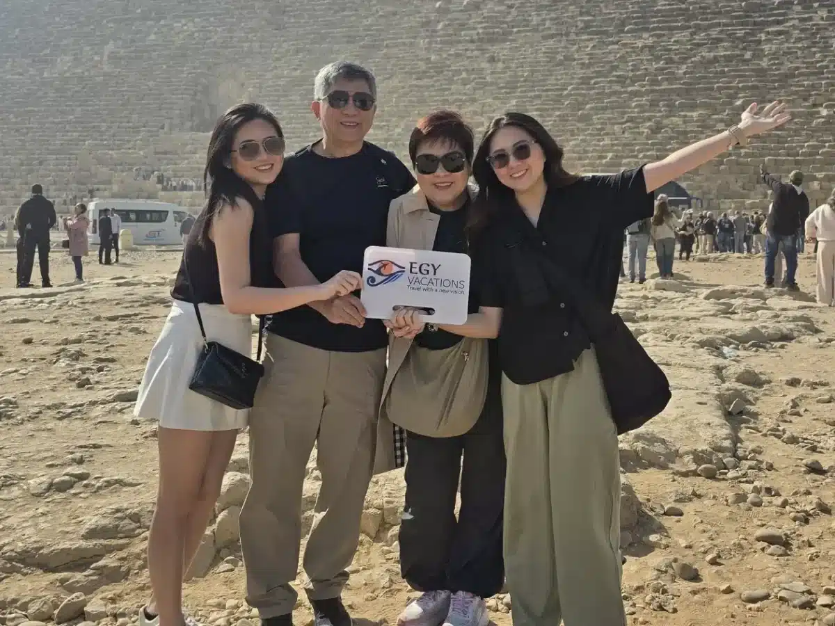 Do You Need a Tour Guide in Egypt? Here’s Why It’s Worth It 2 A family on a guided tour in Egypt posing with an Egy Vacations sign at the Great Pyramid of Giza.