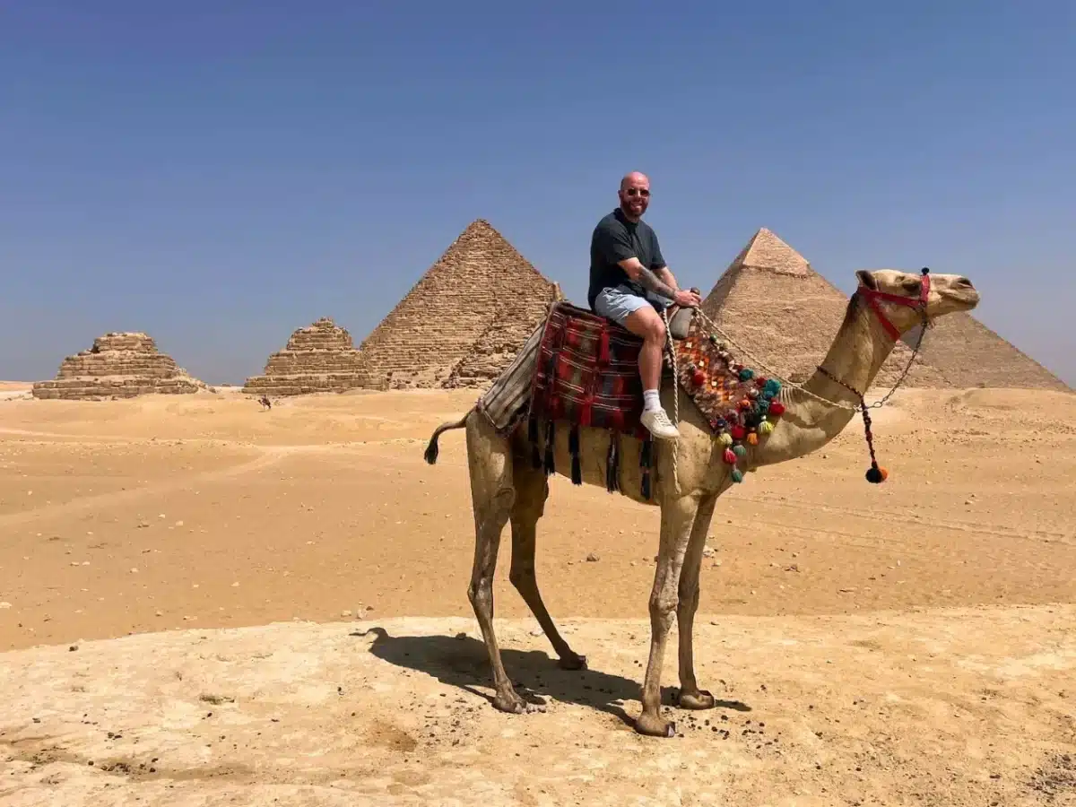 Amazing shot of a man riding a camel in front of the Giza Pyramids - Solo Travel to Egypt